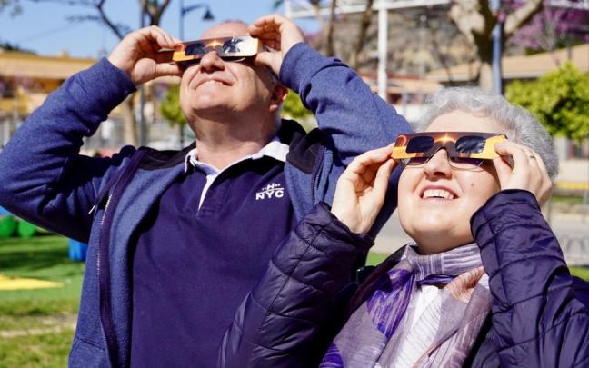 Una pareja contempla un eclipse con una gafas especiales para ello.