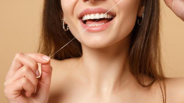 Una mujer se pasa el hilo dental por los dientes. / Freepik Una mujer se pasa el hilo dental por los dientes.
