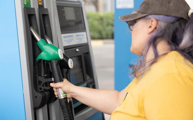 Una mujer repostando gasolina.