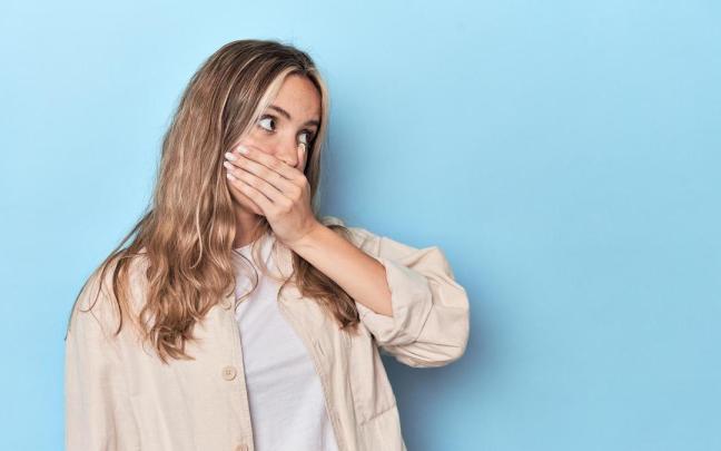 Una mujer se tapa la boca por su mal aliento.