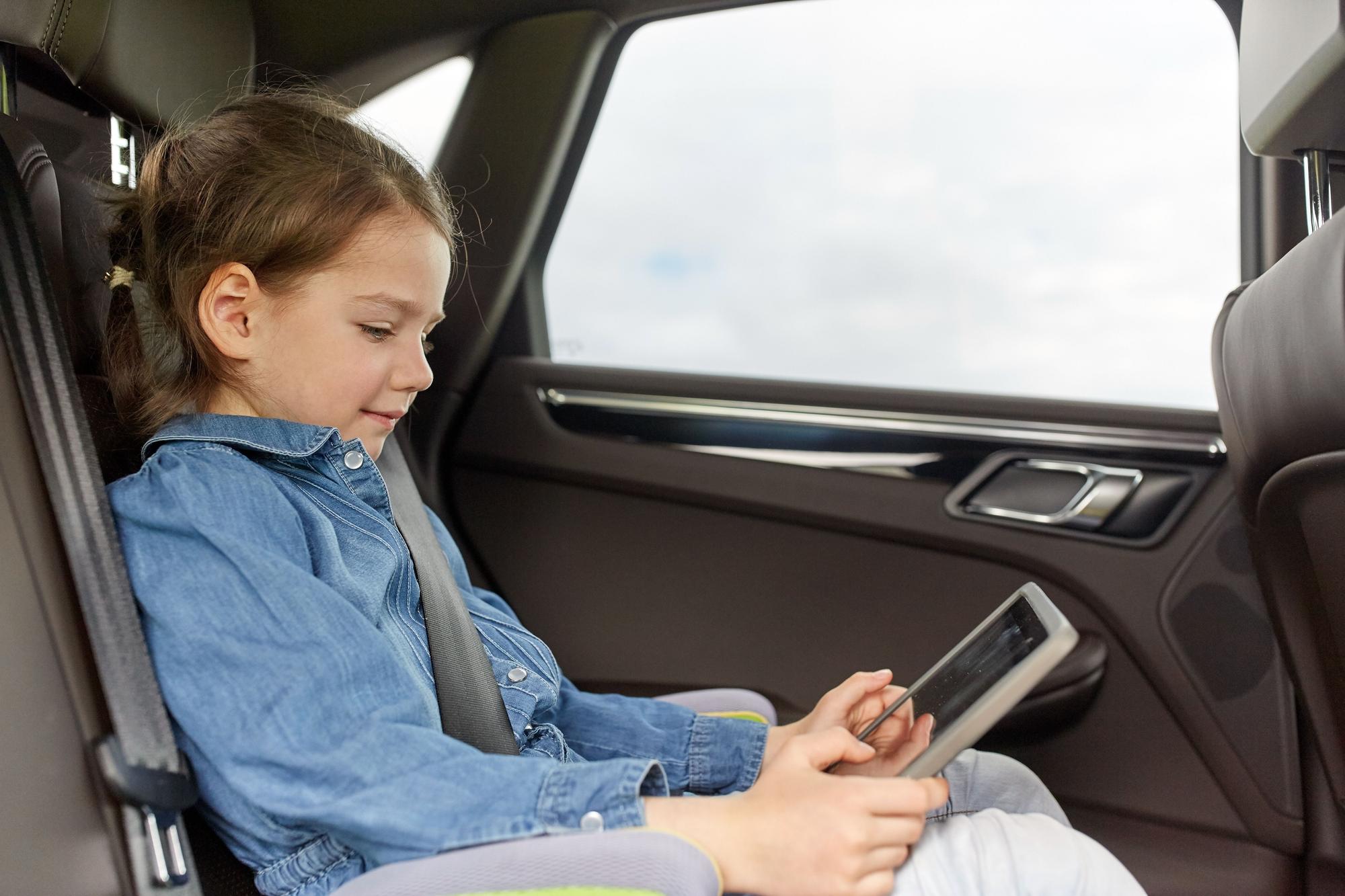Niña con una tablet en el coche.