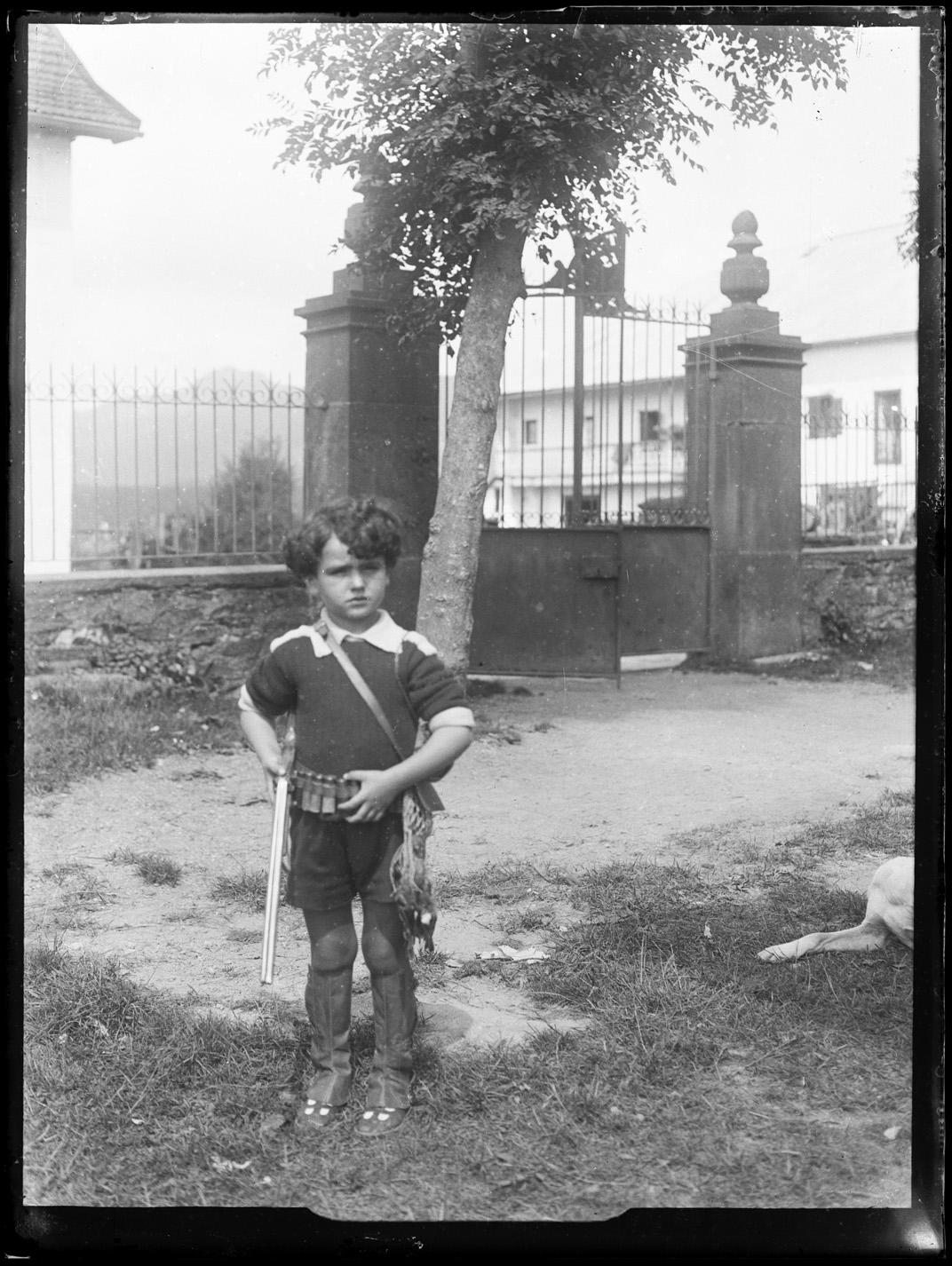 Retrato de niño disfrazado de cazador con canana, polainas, morral y rifle en un jardín, fechado por el Archivo General de Navarra entre 1926 y 1930. Retrato de niño disfrazado de cazador con canana, polainas, morral y rifle en un jardín, fechado por el Archivo General de Navarra entre 1926 y 1930.