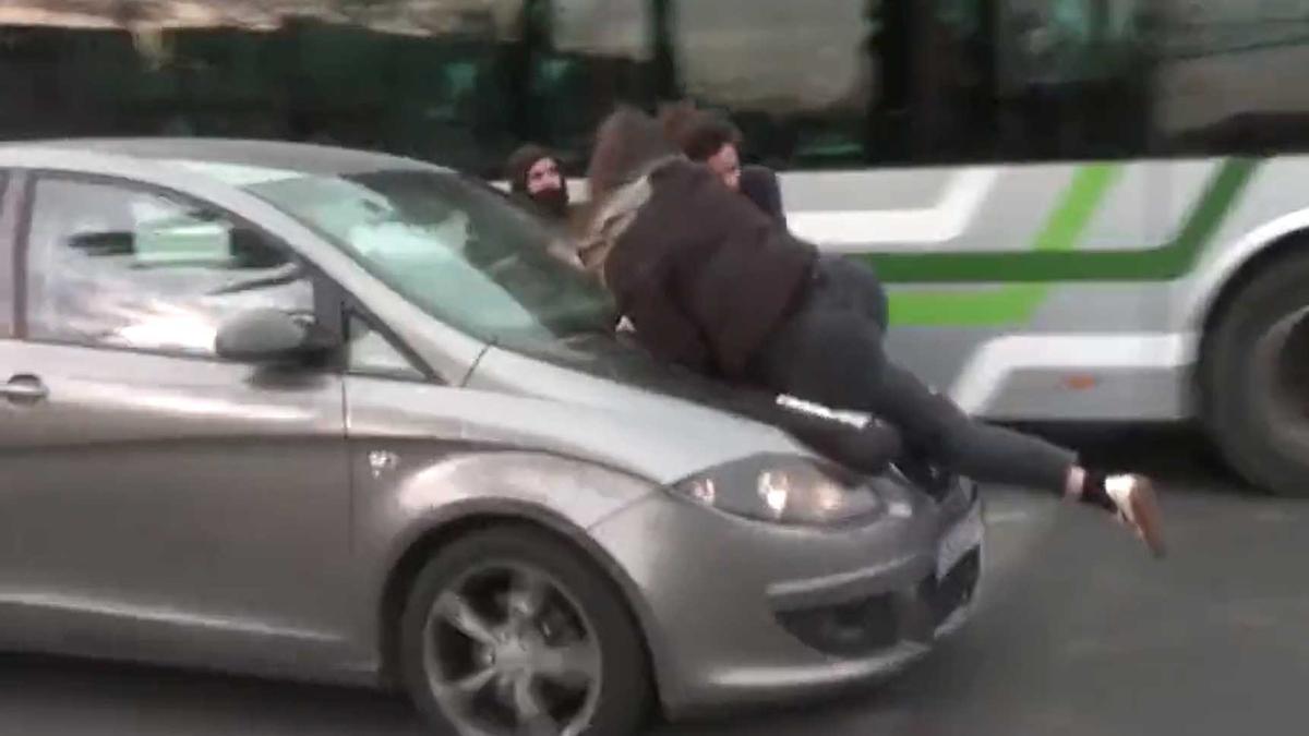 Tres manifestantes sobre el capó del coche.