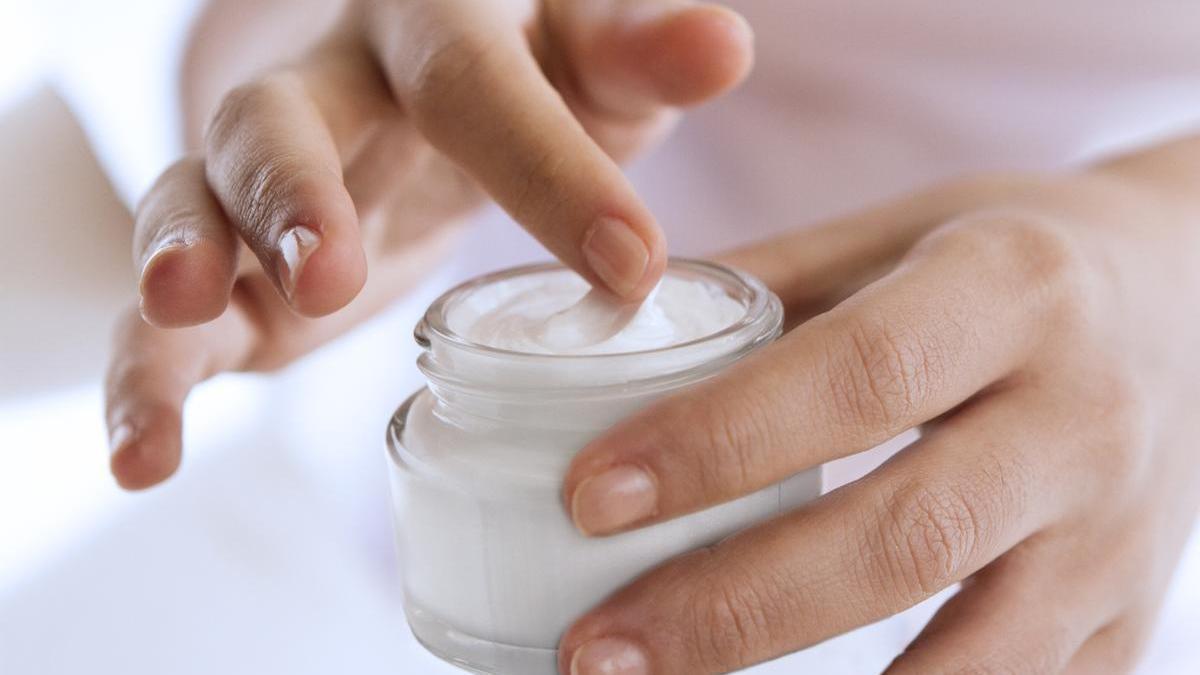 Manos de una mujer que sostiene un frasco de crema.