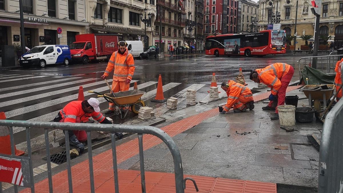 Un grupo de operarios trabajan en los arreglos de una acera en Bilbao.