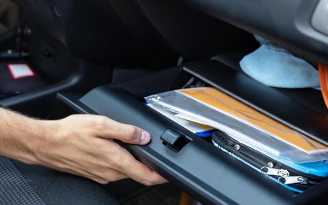 Una persona abre la guantera de un coche.