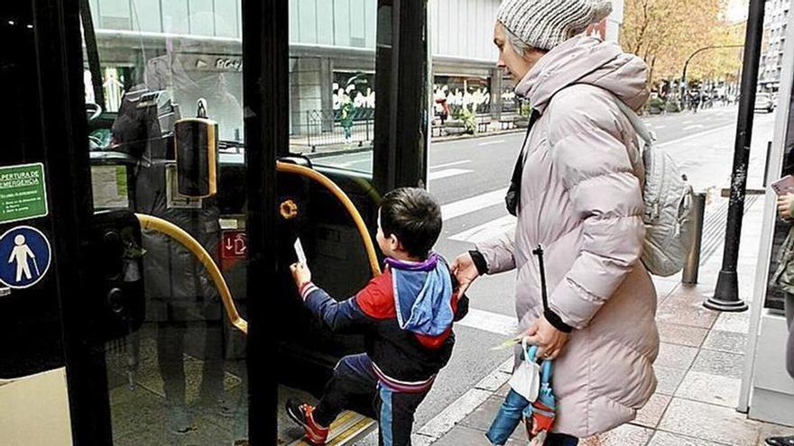 Un niño junto a su madre suben a un autobús urbano.