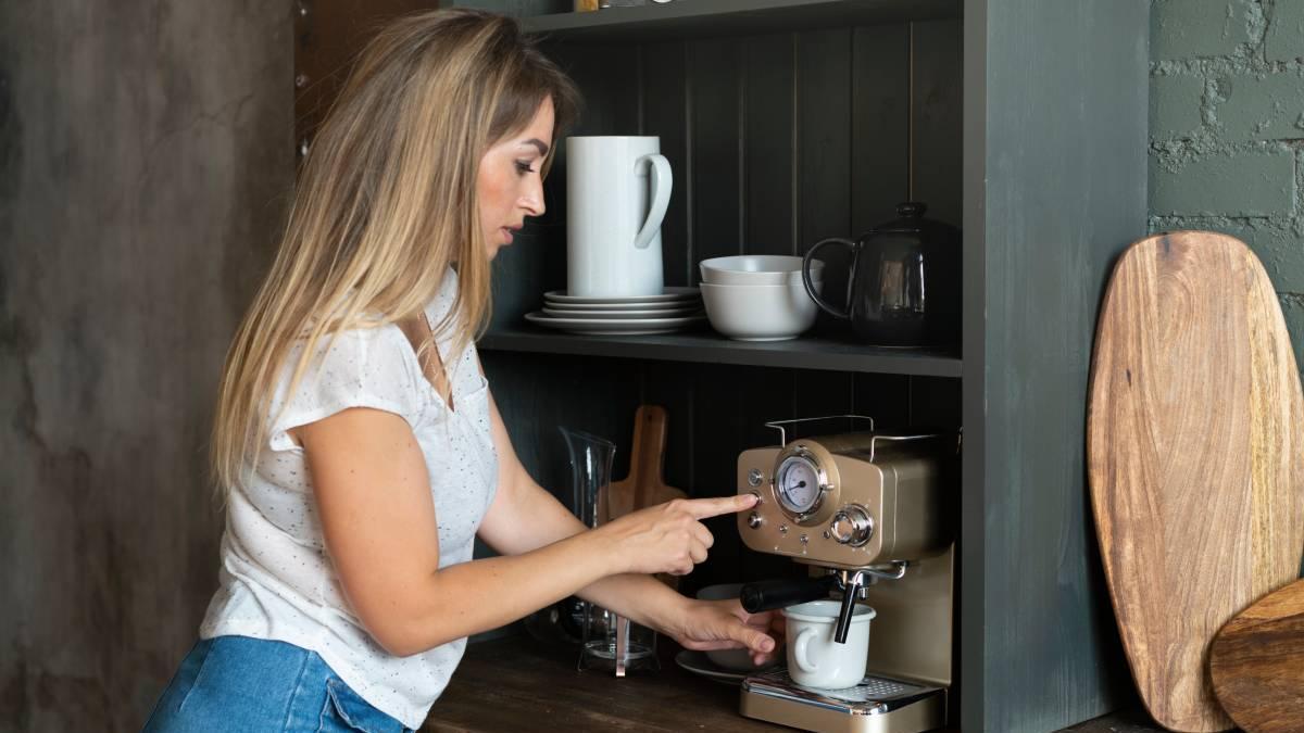 Chica prepara un café en su cafetera de casa.