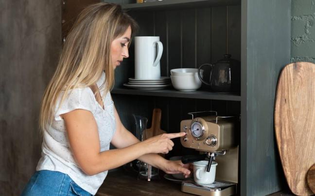 Chica prepara un café en su cafetera de casa.
