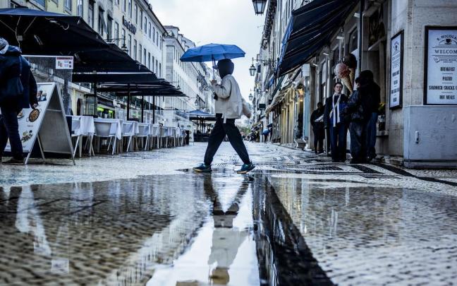 Un hombre pasea por Lisboa bajo un paraguas.