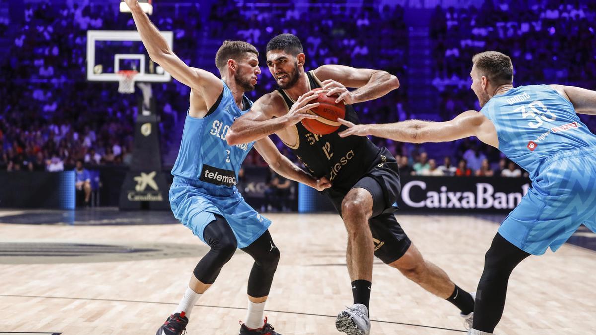 El jugador español Santi Aldama trata de escapar de dos jugadores de Eslovenia, durante el partido del Torneo Centenario de la FEB disputado este viernes en el pabellón Martín Carpena, en Málaga