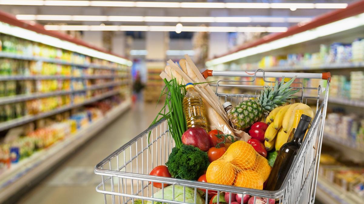 Un carro de la compra lleno en un pasillo de un supermercado.