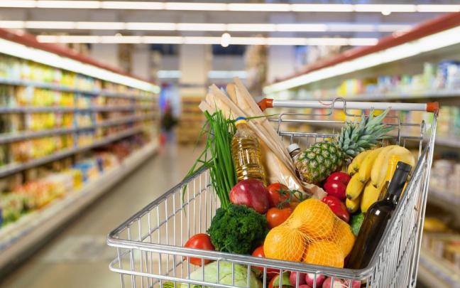 Un carro de la compra lleno en un pasillo de un supermercado.