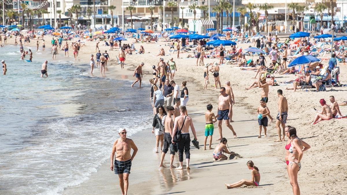 Centenares de personas tomando el sol y refrescándose en una playa.