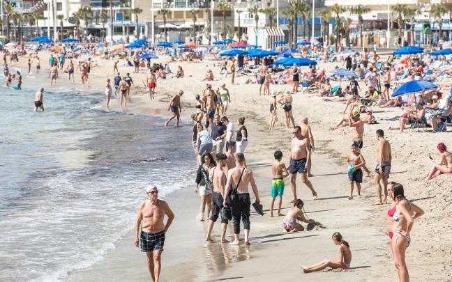 Centenares de personas tomando el sol y refrescándose en una playa.