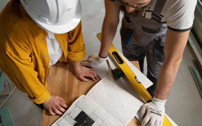 Dos trabajadores miran un plano.