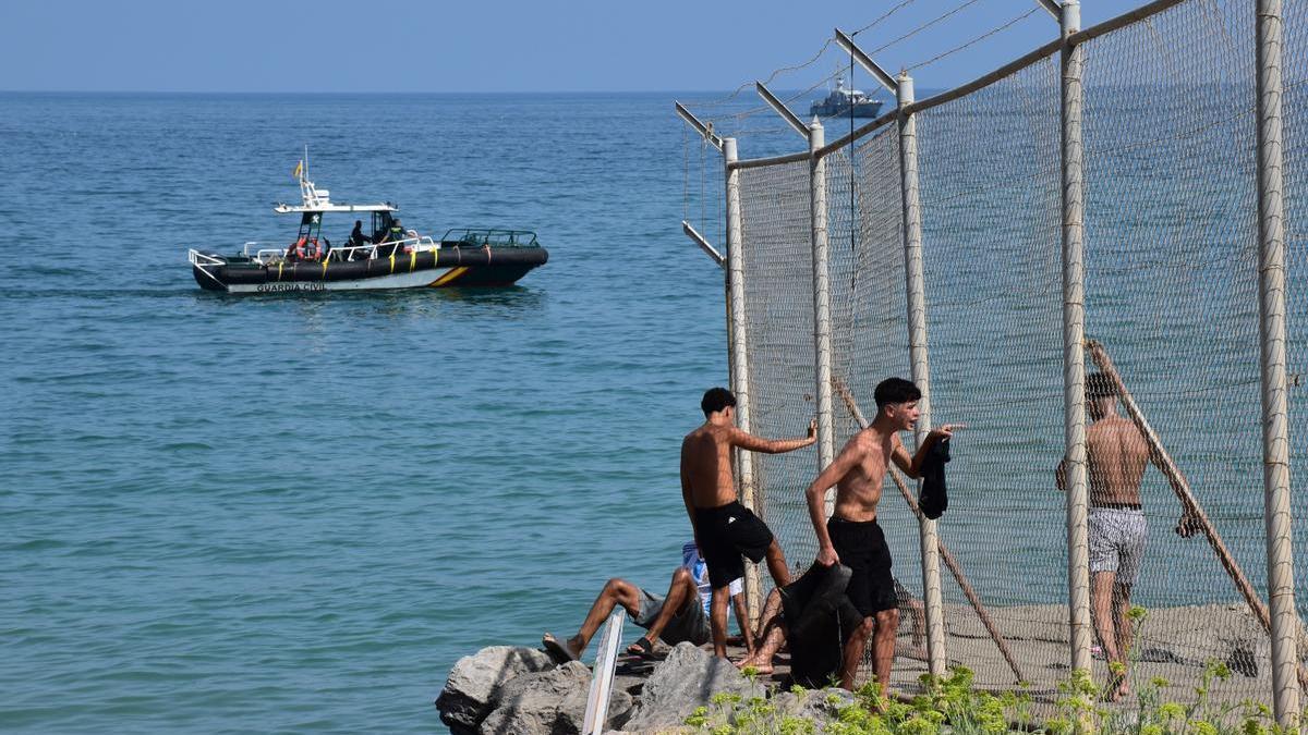 Varias personas cruzan la frontera en Ceuta.