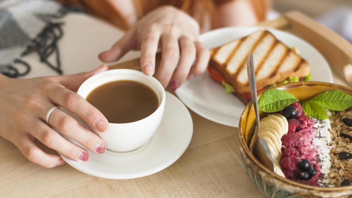 Una chica disfruta de su desayuno, acompañado de un café con leche