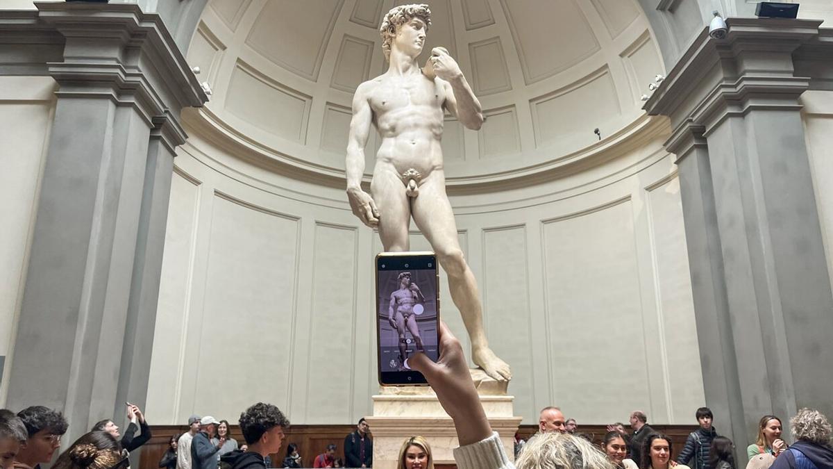 Una visitante toma una fotografía de la escultura del David de Miguel Ángel en la Galería de la Academia de Florencia, Italia.