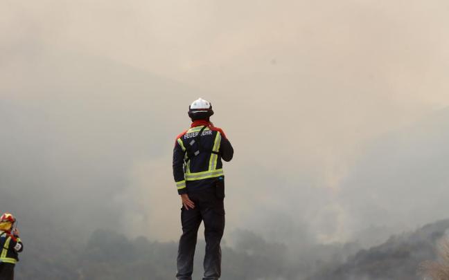 Varios bomberos observan el incendio forestal