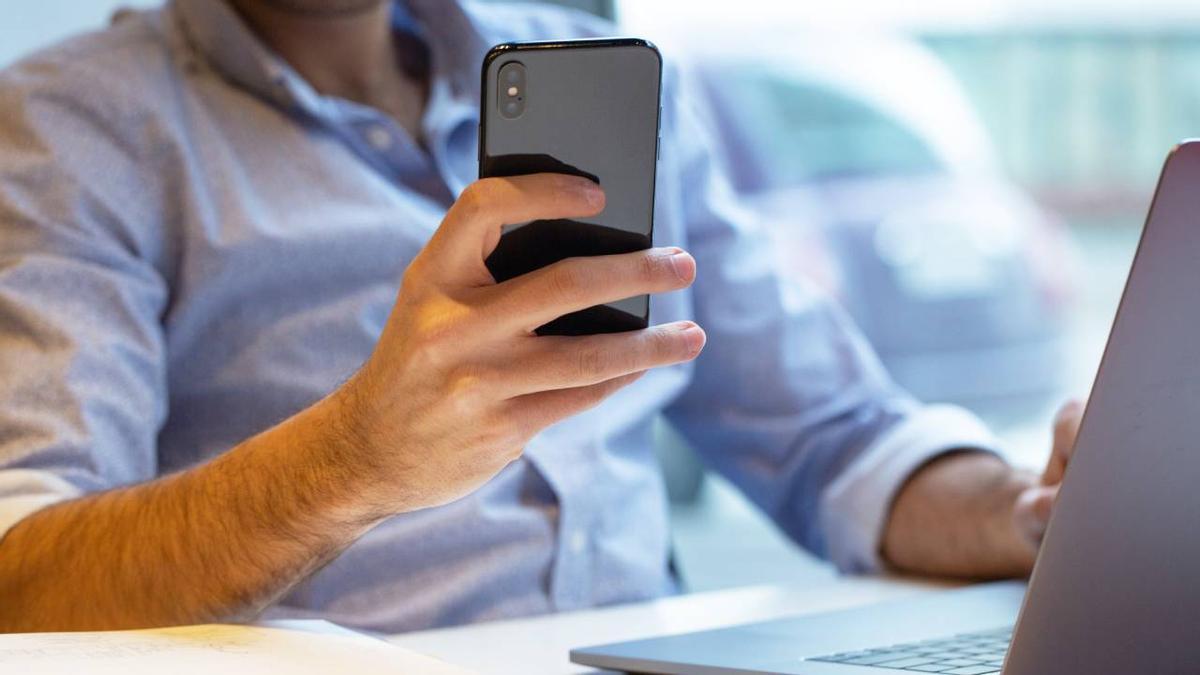 Hombre revisa su teléfono móvil.