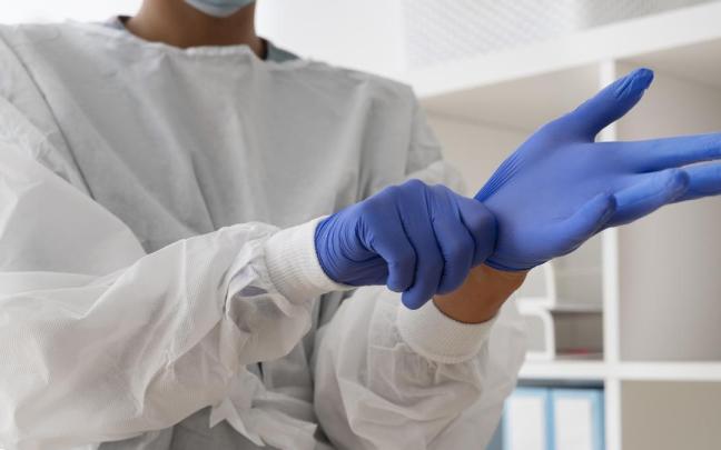 Un sanitario se coloca unos guantes.