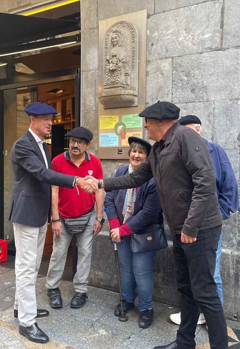 Apretón de manos bajo la talla de la Amatxu de Begoña.