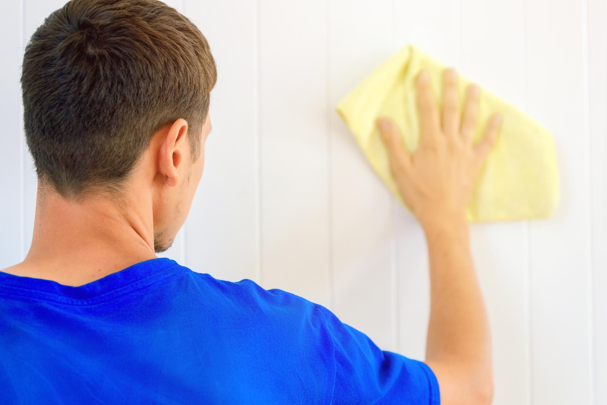 Un hombre pasa una bayeta por una pared.