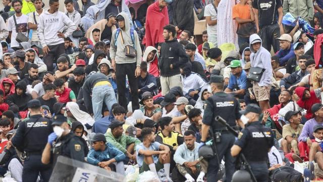 Policías desalojan a migrantes que permanecían en la playa del Trampolín en Ceuta.