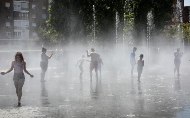 Varias personas se refrescan en un parque