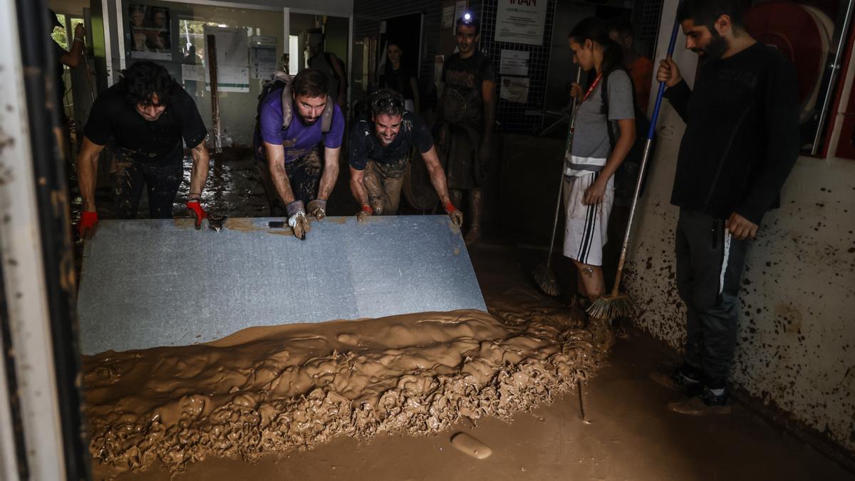 Varias personas ayudan a limpiar los locales inundados por la dana de Valencia