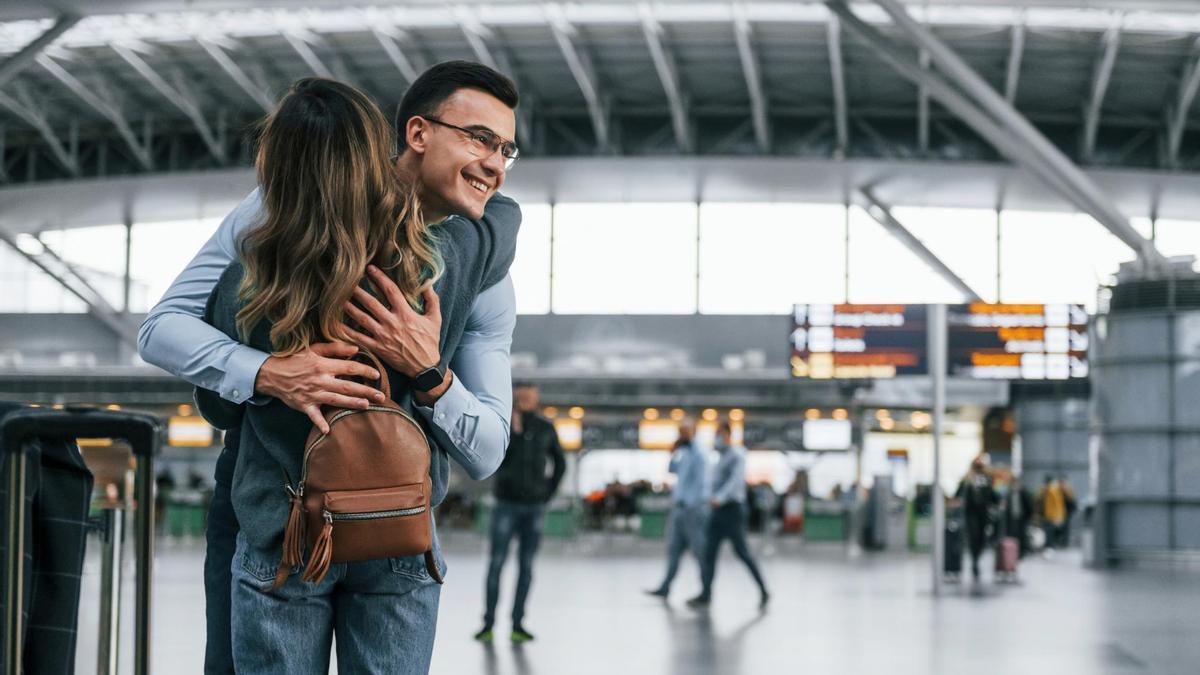 Una pareja se abraza en un aeropuerto.