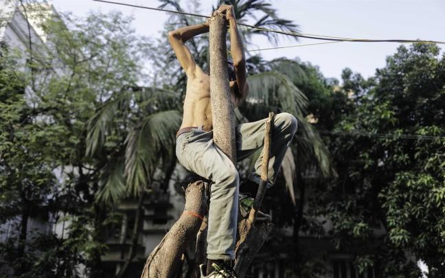 Imagen de archivo de un hombre subido a un poste en Bangladesh.