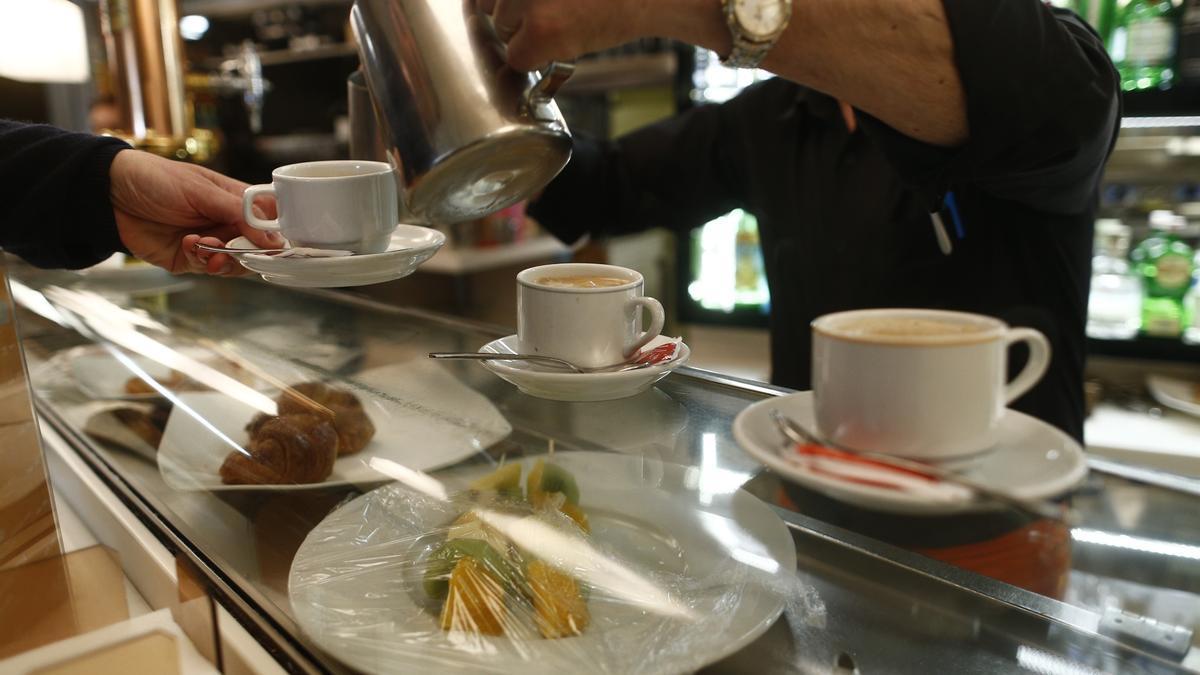 Un empleado de hostelería sirve un café.