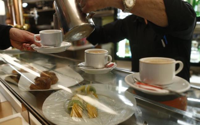 Un empleado de hostelería sirve un café.