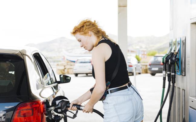 Una mujer llena el depósito de su coche en una gasolinera. Una mujer llena el depósito de su coche en una gasolinera.