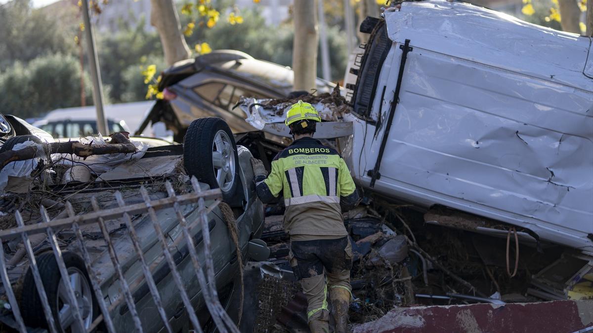 Varios bomberos buscan a personas entre coches