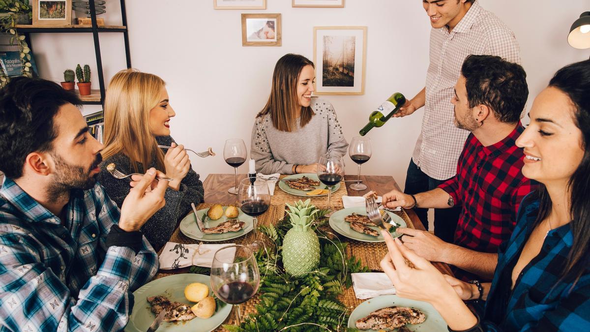 El anfitrión sirve vino a sus invitados durante una comida con amigos.