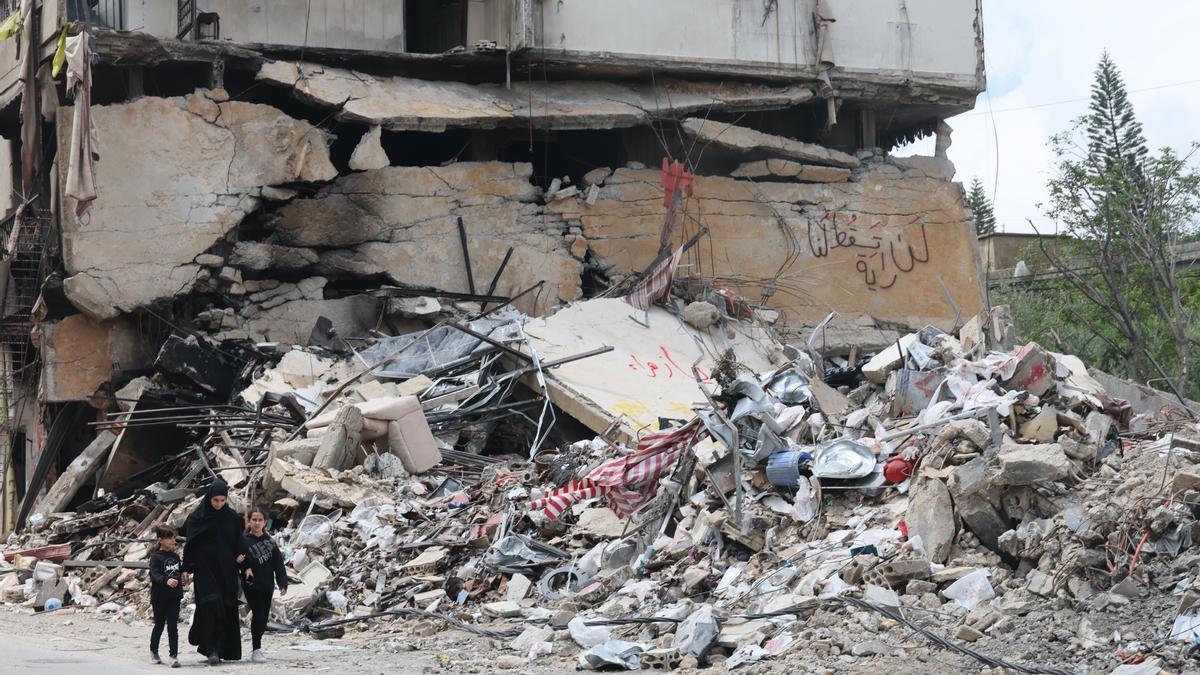Libaneses caminan junto a los escombros de un edificio dañado por un ataque aéreo israelí en el sur.