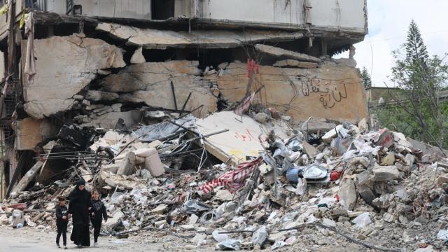 Libaneses caminan junto a los escombros de un edificio dañado por un ataque aéreo israelí en el sur.