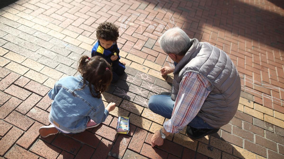 Un hombre mayor juega con unos niños, en la plaza San Pedro de Sestao.