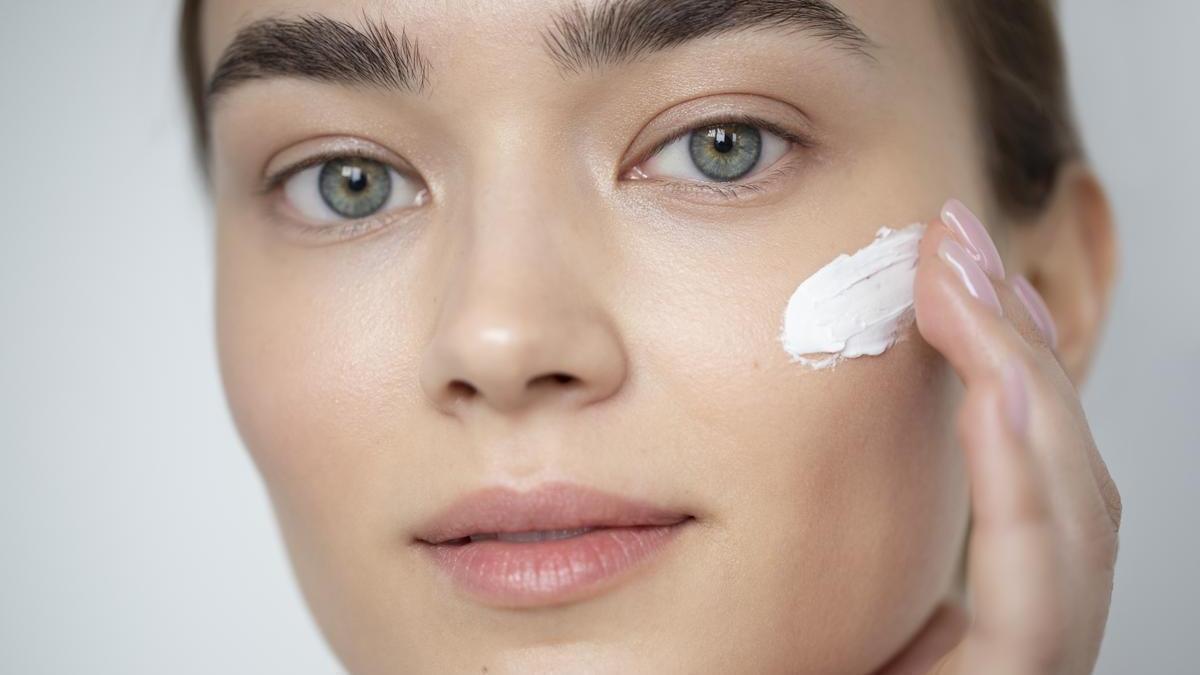 Primer plano del rostro de una chica aplicándose crema.