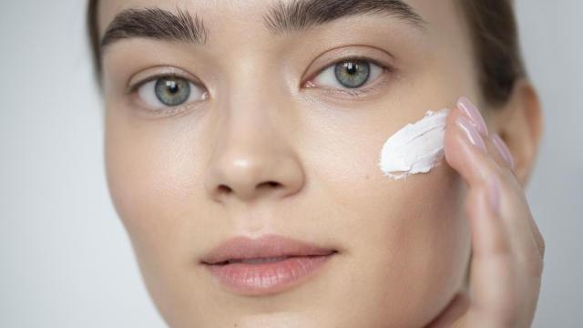 Primer plano del rostro de una chica aplicándose crema.