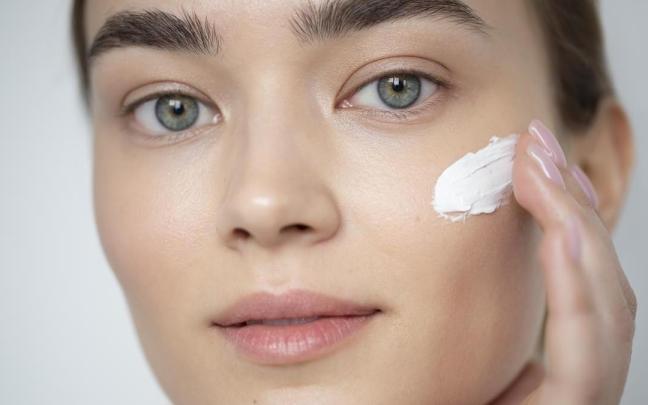 Primer plano del rostro de una chica aplicándose crema.