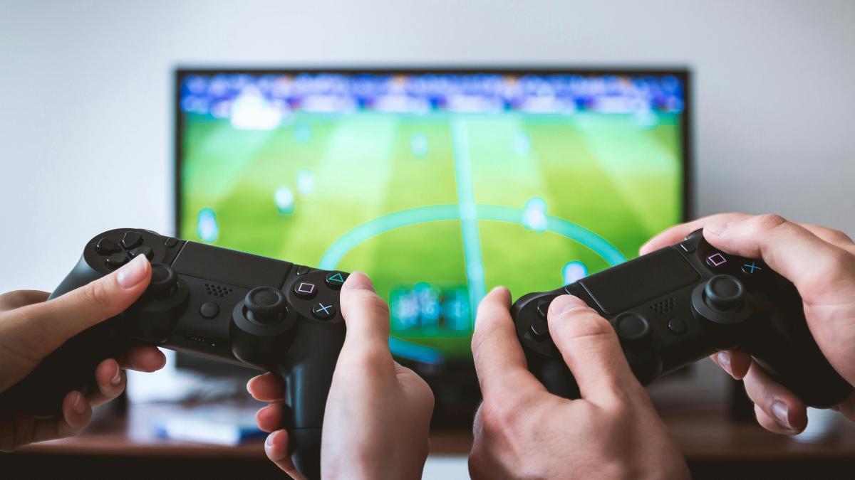 Dos personas juegan a la PlayStation en el salón de una casa