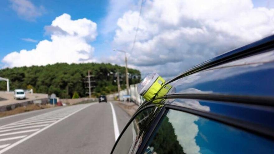 Un vehículo estacionado en el arcén de una carretera con la baliza V16 apagada