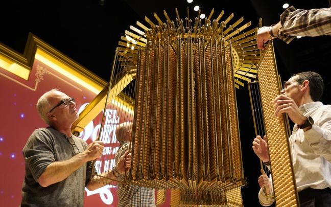 Personal de Loterías y Apuestas del Estado cuelgan las liras con las bolas del sorteo de la Lotería de Navidad.