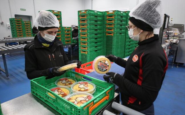 Empleadas trabajando en la cadena de producción de una empresa de alimentación.