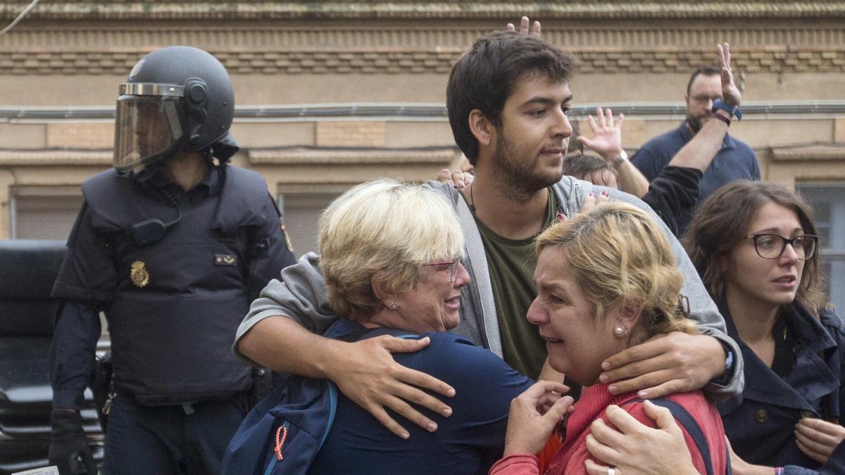 Varias personas ante agentes de la Policía Nacional que evitaron que se pudiera votar en el referéndum del 1 de octubre.