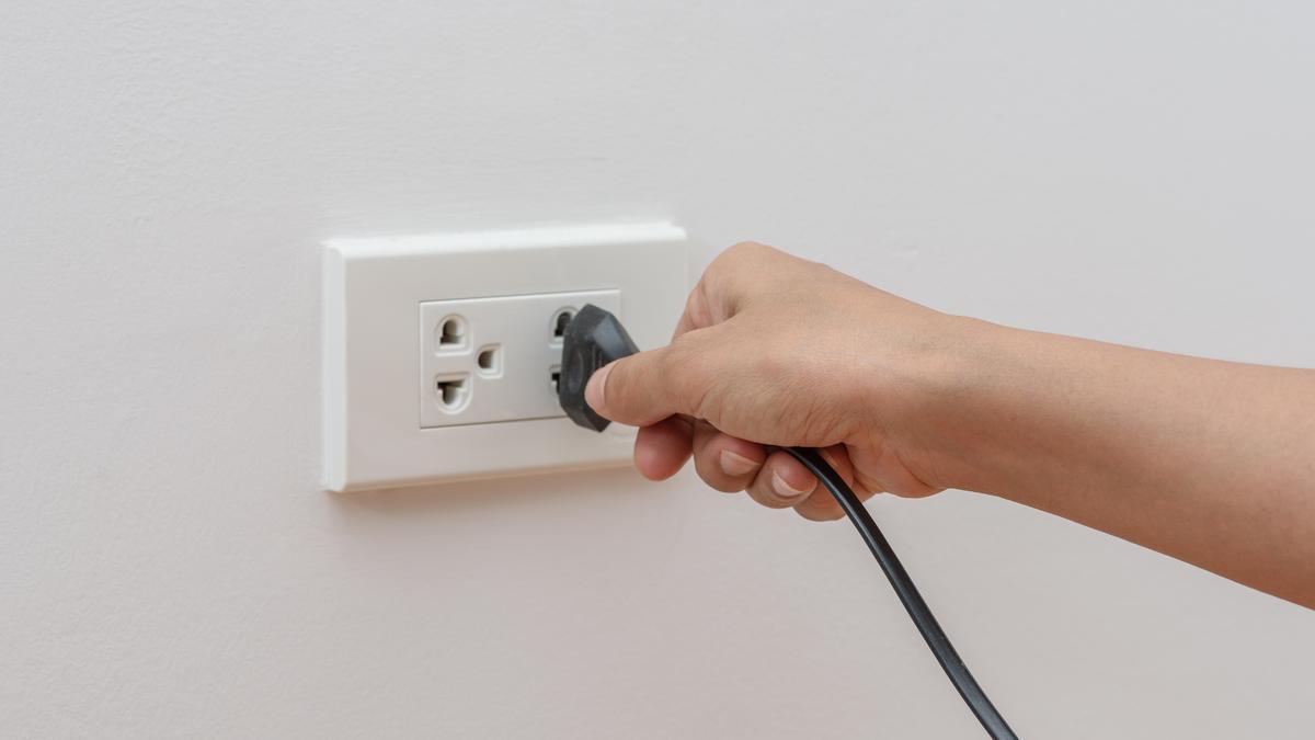 Una persona conecta un aparato a un enchufe eléctrico.